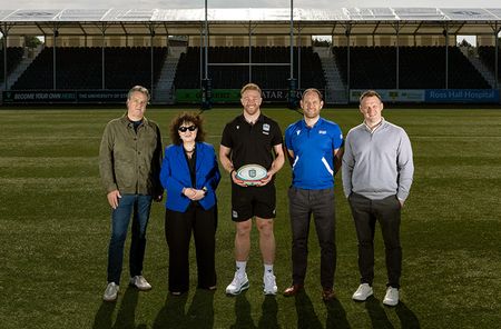 Group photo on a rugby field with Kyle holding a ball at the centre of the image